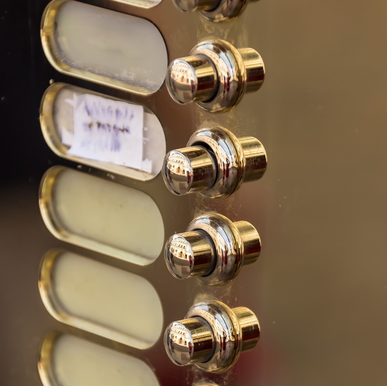 Nahaufnahme mehrerer glänzender Metall-Türklingelknöpfe auf einer Platte.