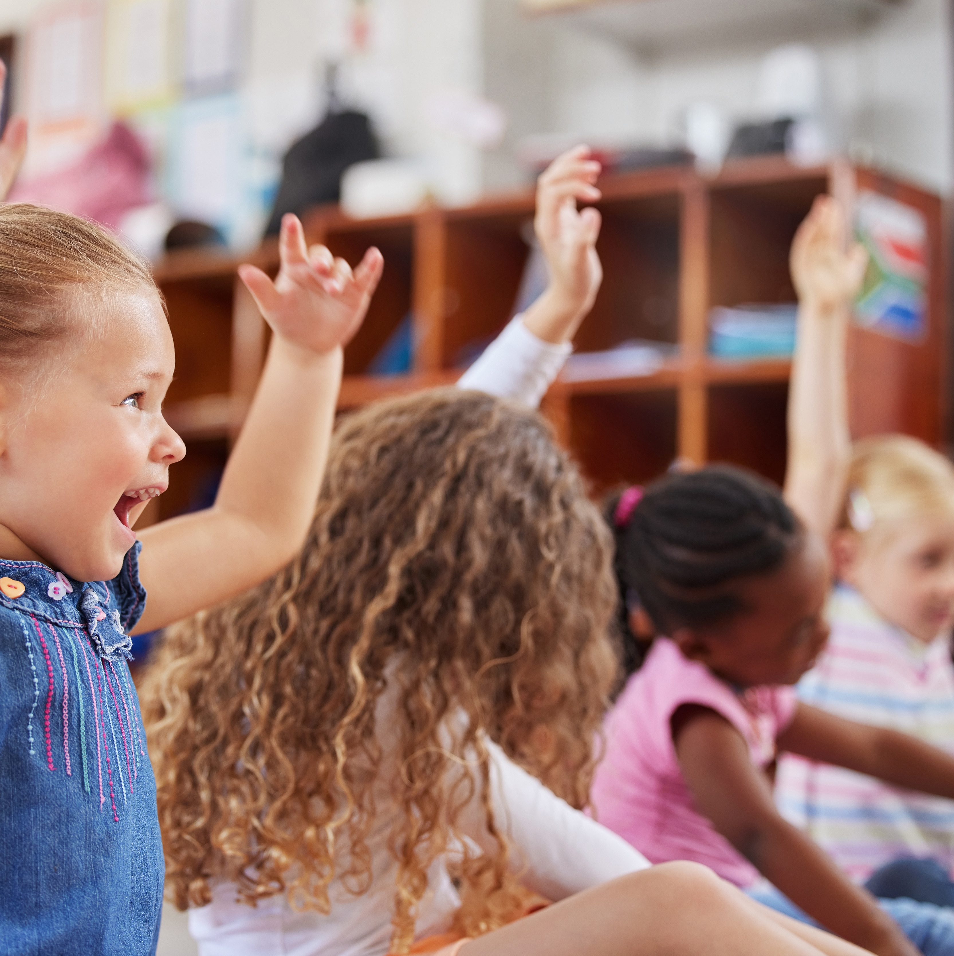 Begeisterte Kinder mit erhobenen Händen in einer Klassenzimmerszene.