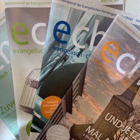 Stapel deutscher evangelischer Kirchenbriefe mit bunter Beschriftung.