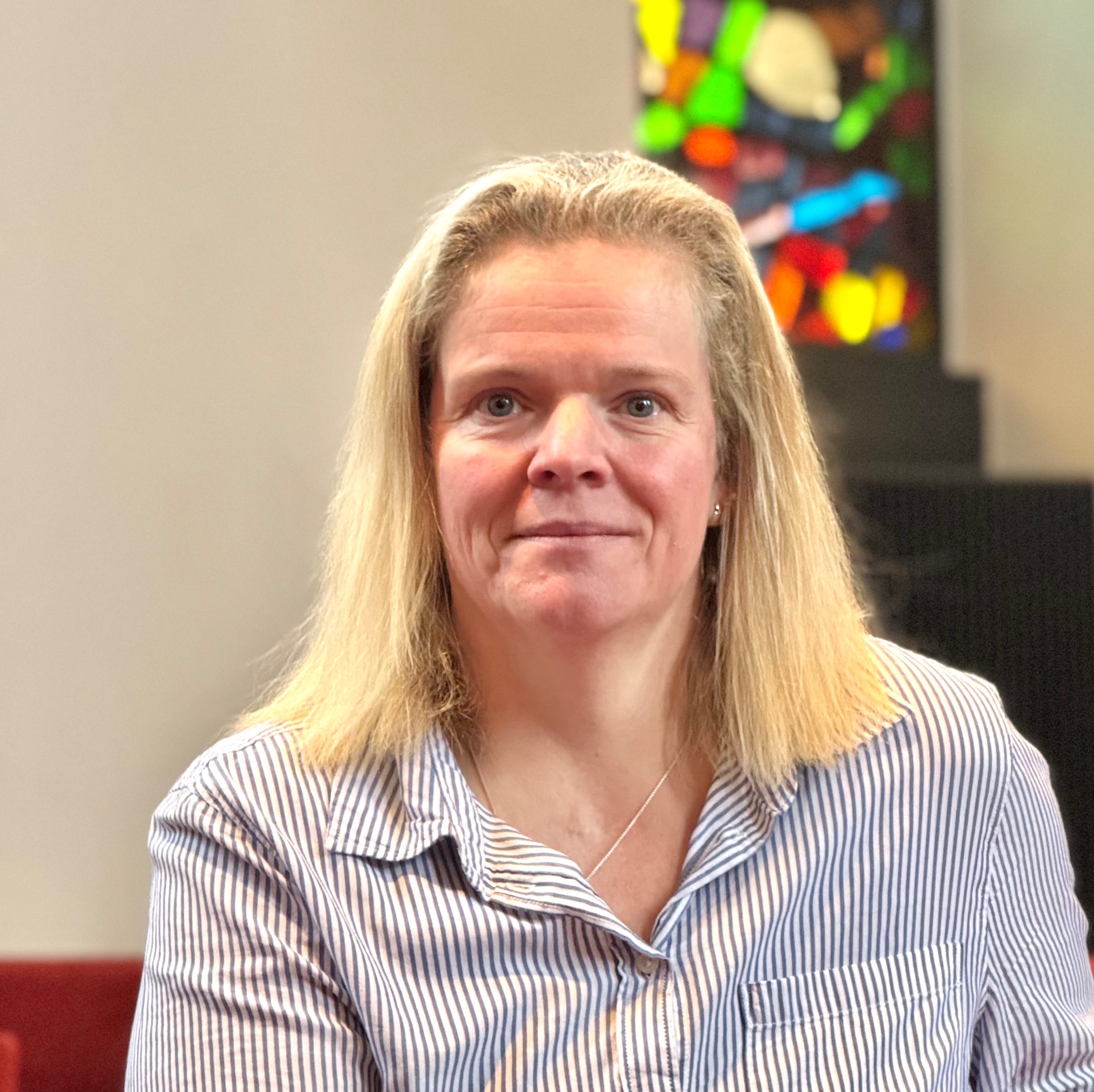 Porträt einer blonden Frau in einem gestreiften Hemd.