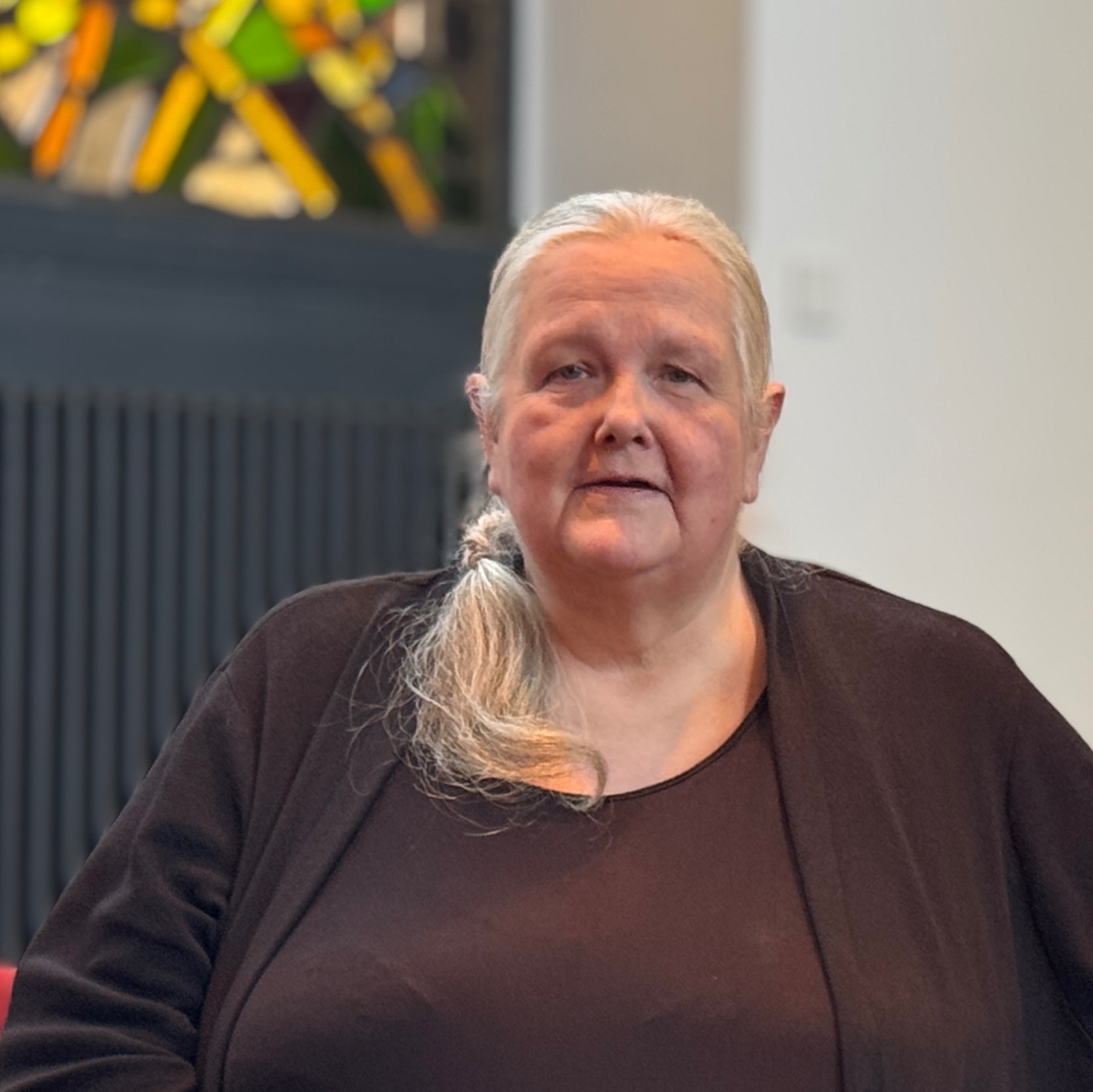 Ältere Frau mit weißen Haaren in einem dunklen Oberteil.